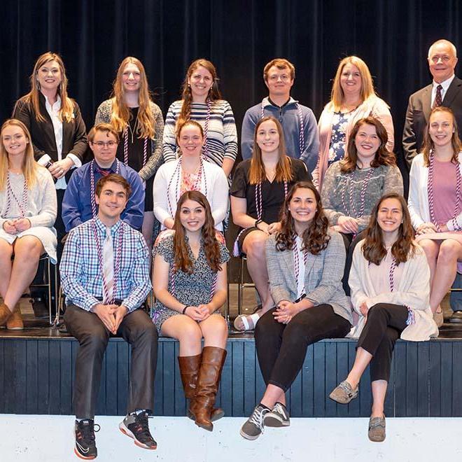 Group of smiling ELA students on the stage at the ELA cording ceremony