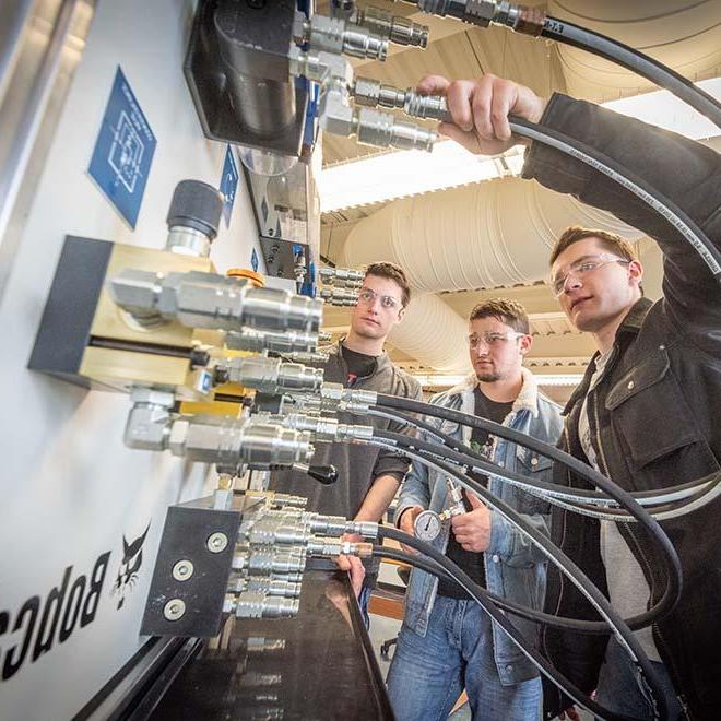 Engineering students working on Bobcat machinery